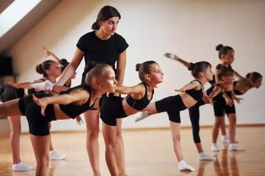 coach-is-helping-group-of-female-kids-practicing-athletic-exercises-together-indoors-photo